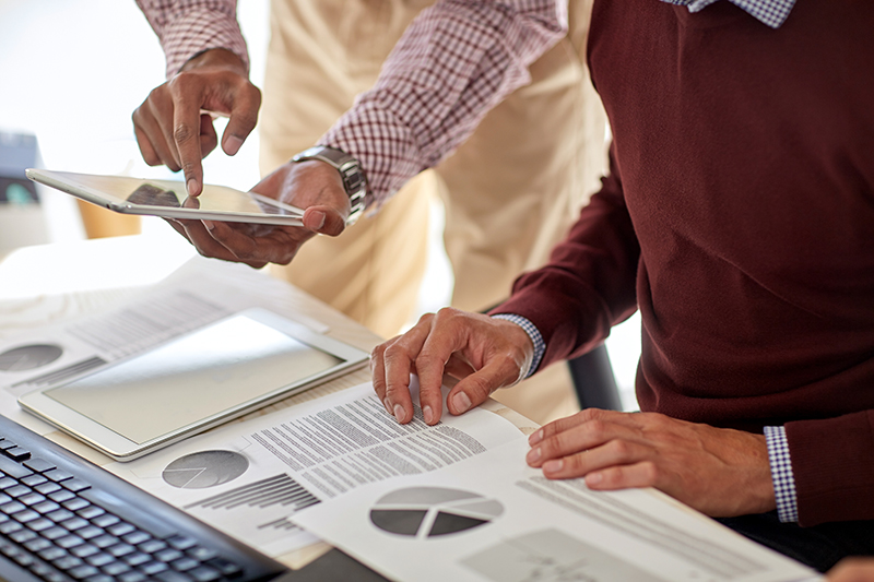 Businessmen with tablet, pc and charts