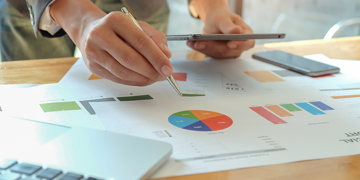 man holding pen pointing to graph