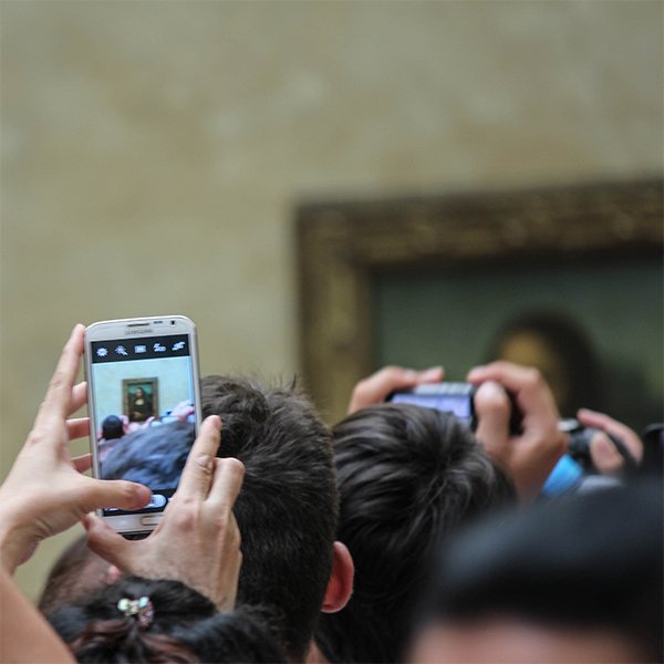 person in a crowd taking a photo of the Mona Lisa on their phone by Image Perception