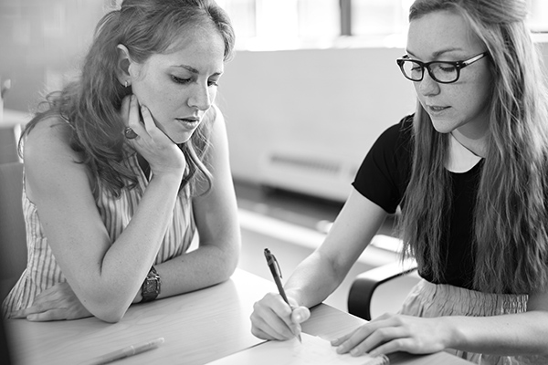 two people sitting at a table discussing some work