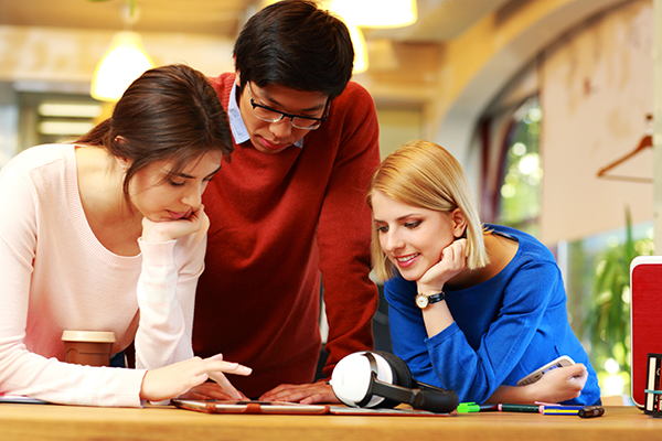 Happy students using a computer tablet together